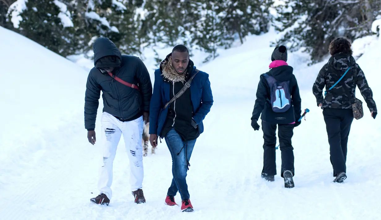 Dua imigran dari Pantai Gading berjalan menuju Colle della Scala (Col de l'Echelle) sebuah jalan yang tertutup salju, untuk melintasi perbatasan antara Italia dan Prancis di Pegunungan Alpen, Italia (13/1). (AFP/Piero Cruciatti)