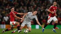 Gelandang Manchester United asal Uruguay #25, Manuel Ugarte (L), melakukan pelanggaran terhadap pemain bertahan Barnsley asal Prancis #06, Ma&euml;l de Gevigney, selama pertandingan sepak bola putaran ketiga Piala Liga Inggris antara Manchester United dan Barnsley di Old Trafford, Manchester, barat laut Inggris, pada Rabu dini hari WIB (18/9/2024). (Paul ELLIS/AFP)