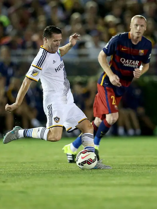 Penyerang LA Galaxy, Robbie Keane berusaha mengoper bola dari hadangan bek Jeremy Mathieu pada laga International Champions Cup 2015 di Rose Bowl, California, Rabu (22/7/2015). Barcelona menang 2-1 atas LA Galaxy. (AFP PHOTO/Stephen Dunn)
