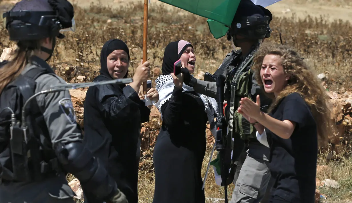 Foto yang diambil pada 26 Mei 2017 menunjukkan Ahed Tamimi (kanan) melakukan protes di depan pasukan Israel di Desa Nabi Saleh. Ahed Tamimi adalah gadis Palestina yang viral karena keberaniannya melawan tentara Israel. (AFP Photo/Abbas Momani)