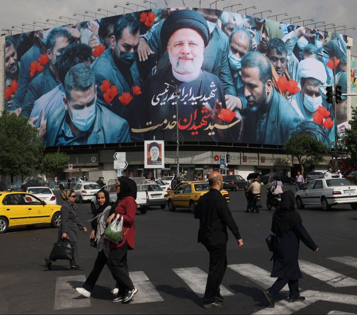 Sejumlah orang berjalan di depan baliho yang menampilkan almarhum Presiden Iran Ebrahim Raisi di Ibu Kota Teheran, Iran, Selasa (21/5/2024). Iran menetapkan masa berkabung selama lima hari untuk mengenang Presiden Ebrahim Raisi.&nbsp;Foto: Majid Asgaripou