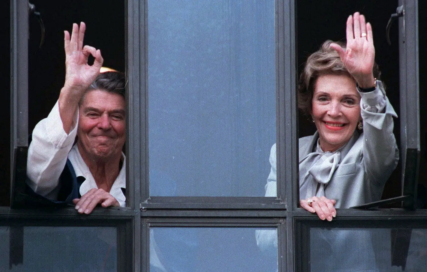Presiden Amerika Serikat Ronald Reagan dan istrinya, Nancy Reagan  melambaikan tangan dari jendela rumah sakit tempatnya dirawat pada 18 Juli 1985 (AP Photo)