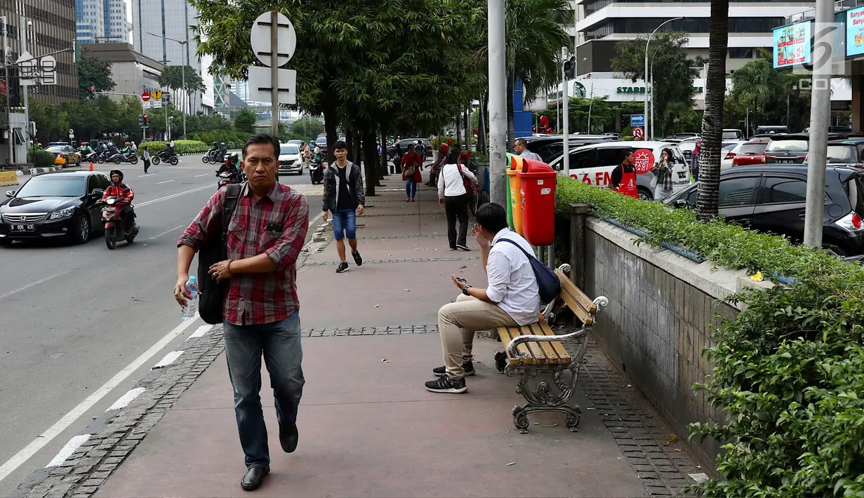 Pejalan kaki berjalan di trotoar kawasan MH Thamrin, Jakarta, Selasa (6/3). Penataan jalan dan trotoar kawasan Sudirman hingga MH Thamrin untuk mempersiapkan keindahan kawasan itu sebagai jalan protokol utama di Jakarta. (Liputan6.com/Immanuel Antonius)