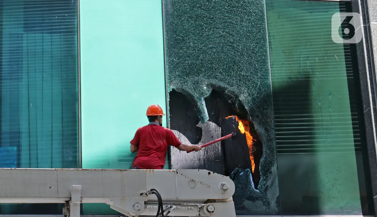 Petugas memecahkan kaca saat berusaha memadamkan kebakaran di Gedung Cyber 1, Jakarta, Kamis (2/12/2021). Suku Dinas Pemadam Kebakaran DKI Jakarta menurunkan 22 unit mobil pemadam kebakaran. (Liputan6.com/Herman Zakharia)