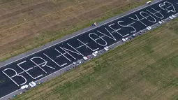 Pemandangan udara dari helikopter menunjukkan meja-meja yang ditata dalam bentuk pesan bertuliskan 'Berlin Loves You' (Berlin Mencintaimu) saat 3.000 warga menghadiri acara Berlin Freedom Dinner di landasan pacu bekas bandara Tegel di Berlin pada 7 Agustus 2021. (Christophe Gateau / DPA / AFP)