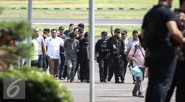 Petugas kepolisian membawa tersangka pembunuhan dan perampokan Pulomas Ridwan Sitorus saat tiba di Bandara Halim Perdana Kusuma, Jakarta, Minggu (1/1). (Liputan6.com/Faizal Fanani)