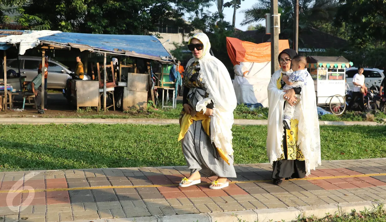Penyanyi Syahrini diikuti sang mama berjalan menuju tempat salat Idul Adha 1437 H di taman Tanah Sereal, Bogor, Senin (12/9). Syahrini memakai baju muslim bermotif, dilengkapi dengan luaran warna putih plus kacamata hitam. (Liputan6.com/Herman Zakharia)