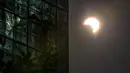 Bulan bergerak menutupi matahari saat fase gerhana matahari cincin di Hong Kong, Kamis (26/12/2019). Gerhana matahari cincin yang terjadi pada hari ini dapat diamati dari sejumlah wilayah mulai Afrika timur, seluruh Asia, Samudera India, dan Australia utara. (Anthony WALLACE/AFP)