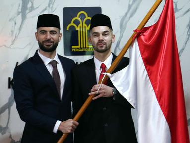 Pemain sepak bola Sandy Walsh (kanan) dan Jordi Amat (kiri) memegang bendera Merah Putih usai menjalani Sumpah Janji Setia Pewarganegaraan di Kantor Wilayah Kementerian Hukum dan HAM DKI Jakarta, Kamis (17/11/2022). Pemain sepak bola naturalisasi asal Belanda dan Spanyol, Sandy Walsh dan Jordi Amat, resmi menjadi Warga Negara Indonesia (WNI) setelah pengambilan prosesi pengambilan sumpah secara bersamaan yang digelar secara tertutup. (Liputan6.com/Herman Zakharia)