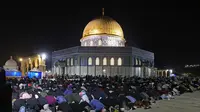 Muslim Palestina menjalani ibadah salat saat memburu malam Lailatul Qadar di luar Kubah Batu (Dome of the Rock) di kompleks Masjid Al-Aqsa di Yerusalem (8/5/2021). (AFP/Ahmad Gharabli)