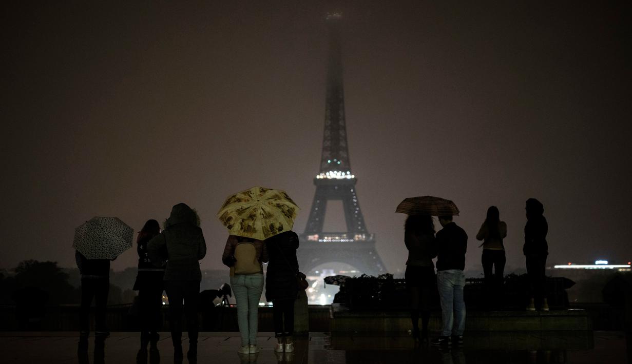 Pengunjung berkumpul di alun-alun Trocadero ketika lampu Menara Eiffel dipadamkan di Paris, Senin (2/10). Pemadaman lampu menara yang menjadi ikon Negara Prancis ini sebagai bentuk penghormatan untuk korban penembakan di Las Vegas. (AP/Kamil Zihnioglu)