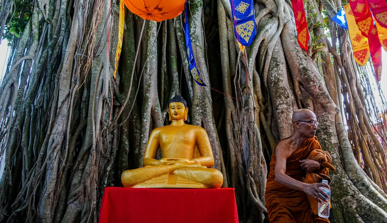 Seorang biksu berdiri dekat patung Buddha saat berziarah ke Candi Borobudur, Magelang, Jawa Tengah, Sabtu (18/52019). Ziarah yang diikuti oleh para biksu dan umat Buddha tersebut untuk merefleksikan ajaran Sang Buddha serta menyambut Waisak 2563 BE/2019. (OKA HAMIED/AFP)