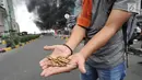 Seorang warga menunjukkan peluru dari kendaraan Polisi yang terbakar di Jalan Brigjen Katamso, Slipi, Jakarta, Rabu (22/5/2019). Belum diketahui penyebab terbakarnya dua bus yang terparkir bersama bus polisi lainnya dilokasi tersebut. (merdeka.com/Arie Basuki)