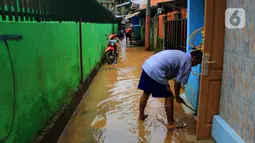 Warga membersihkan lumpur sisa banjir di kawasan Bidara Cina, Kecamatan Jatinegara, Jakarta Timur, Selasa (25/2/2020). Baru satu hari air surut, kawasan Bidara Cina yang bersebelahan dengan Kali Ciliwung kembali mengalami banjir. (merdeka.com/magang/ Muhammad Fayyadh)