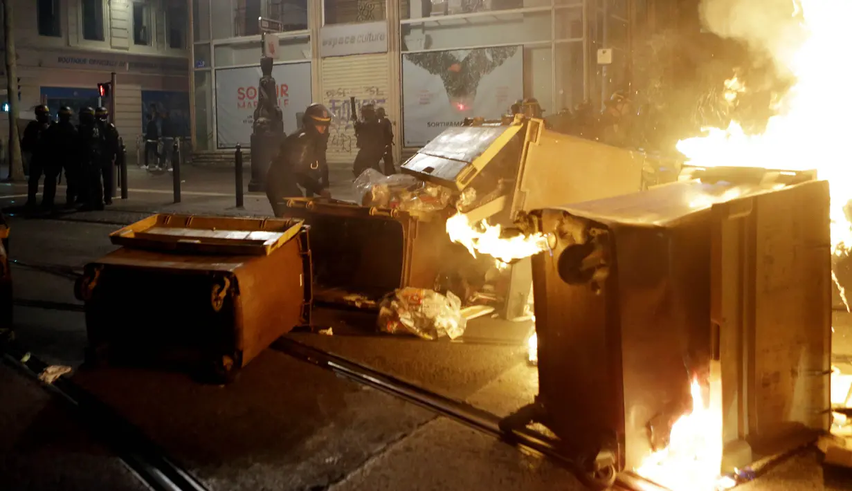 Polisi mengangkat tempat sampah yang dibakar fans Marseille usai tim nya kalah dari Atletico Madrid final Liga Europa di Vieux Port, Prancis, Rabu, (16/5/2018). Atletico Madrid menang 3-0 atas Marseille. (AP/Claude Paris)
