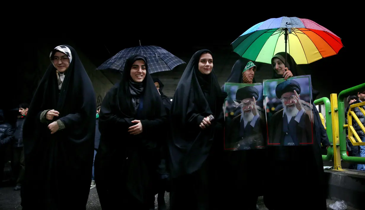 Perempuan Iran membawa poster Ayatollah Ali Khamenei saat memperingati 40 tahun Revolusi Islam Iran di Teheran, Senin (11/2). Ratusan ribu orang mengikuti peringatan 40 tahun Revolusi Islam Iran. (AP Photo/Ebrahim Noroozi)