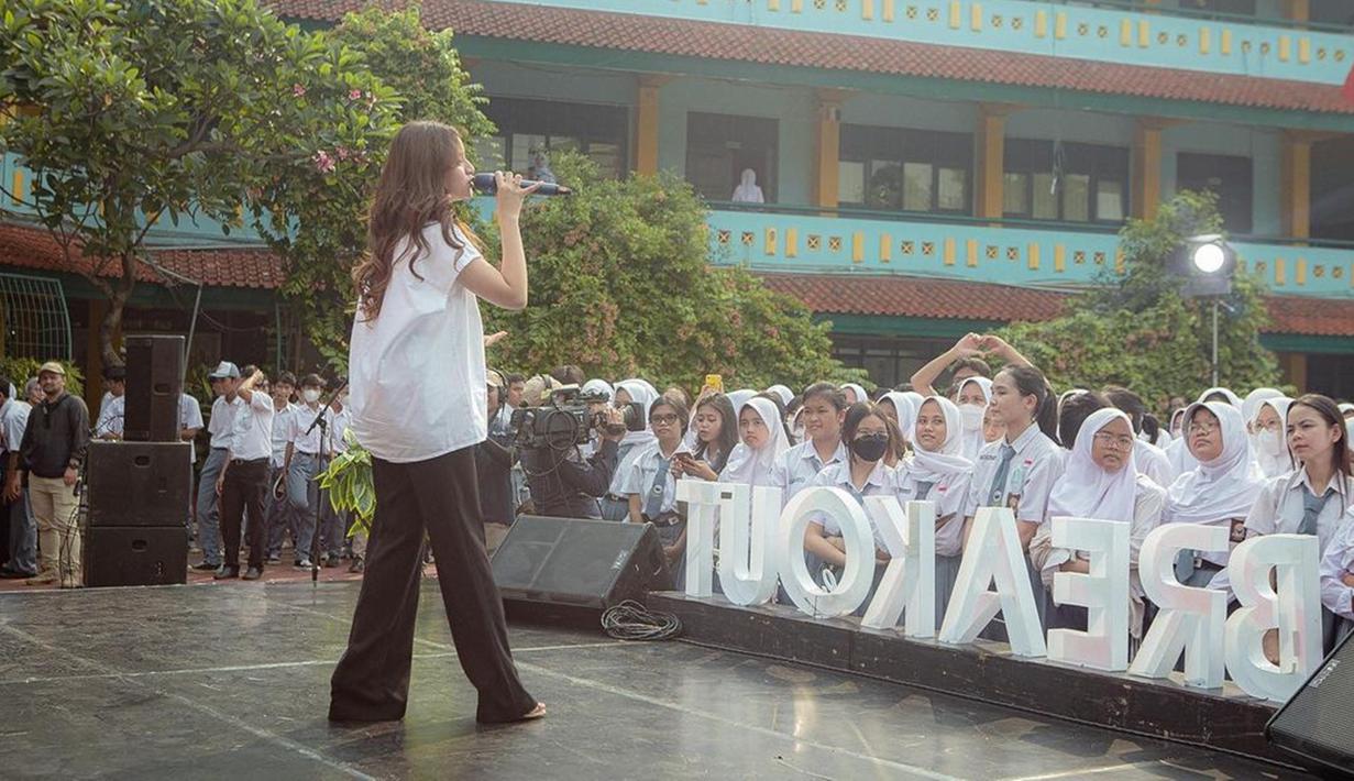 Anggi Marito membagikan potret keseruannya saat tampil bernyanyi di SMAN 47 Jakarta. Perempuan kelahiran 6 Maret 2002 itu tampil kasual dengan kemeja putih dan celana panjang hitam. Para pelajar tampak ikut bernyanyi bareng Anggi yang memukau di atas panggung. (Liputan6.com/IG/@anggimarito)