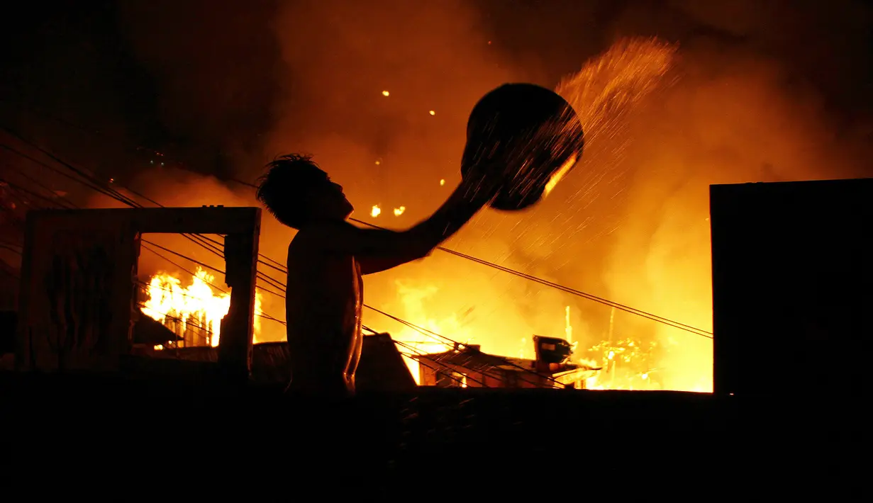 Seorang pria berusaha menyiramkan air saat kebakaran di lingkungan Educandos, di Manaus, Brasil (17/12). Kebakaran diduga disebabkan oleh ledakan panci presto yang menghanguskan ratusan rumah warga. (AP Photo/Edmar Barros)