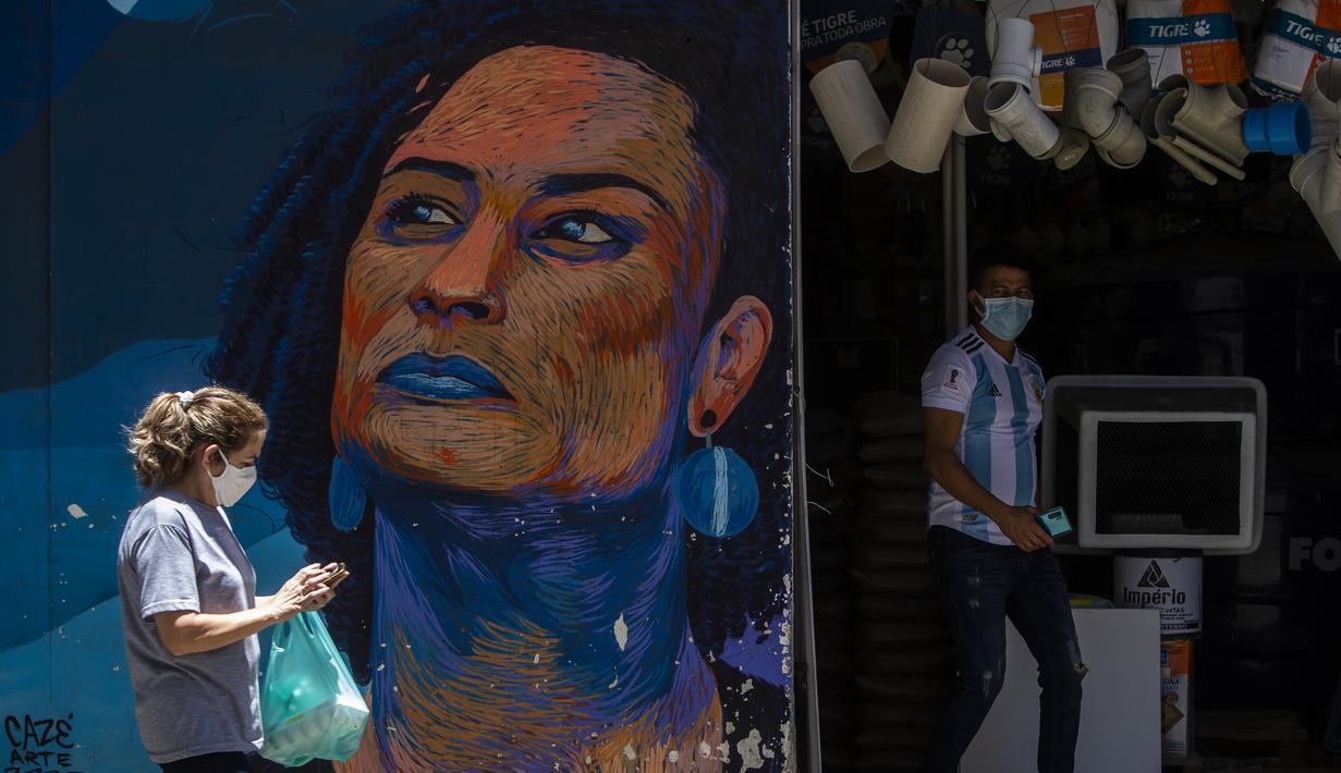 Seorang wanita melewati lukisan perkotaan yang menampilkan gambar mendiang anggota dewan Marielle Franco, yang dibuat seniman Caze dan produser Pedro Rojao, di Rio de Janeiro, 17 November 2021. Brasil menyambut Hari Kesadaran Kulit Hitam yang diperingati setiap 20 November. (AP Photo/Bruna Prado)