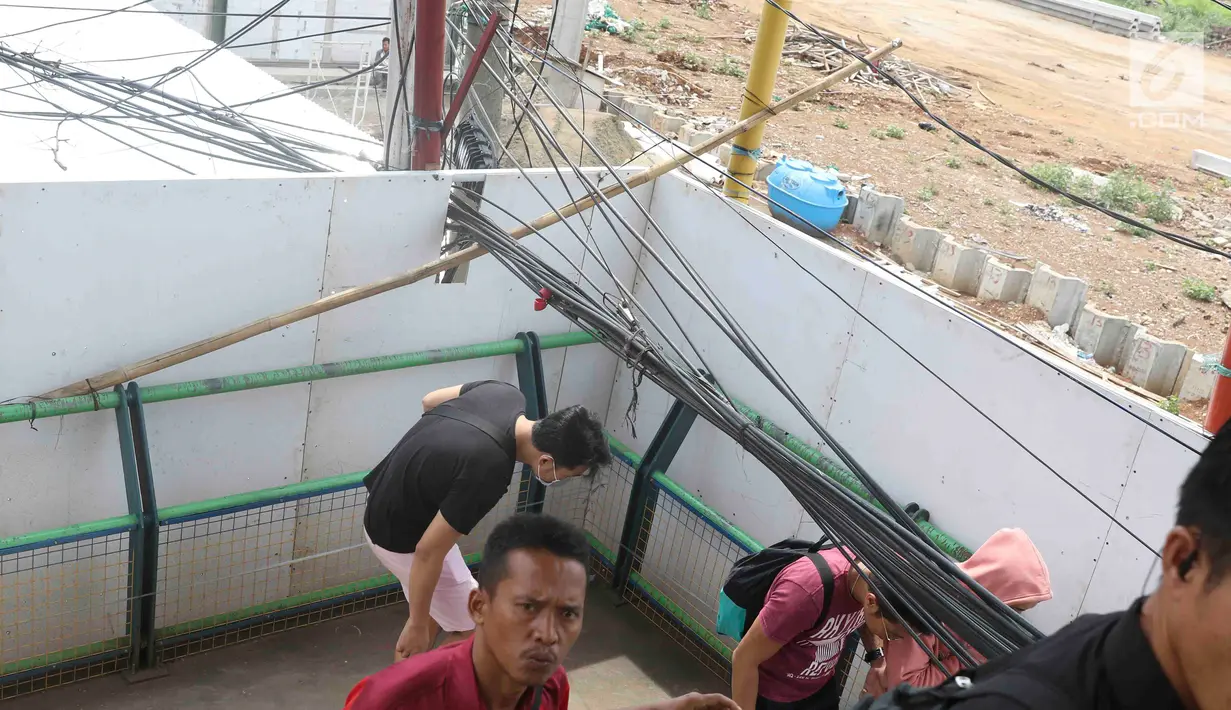 Pejalan kaki melintasi jembatan penyeberangan orang yang terhalang instalasi kabel di Depok, Jawa Barat, Sabtu (8/12). Selain mengganggu kenyamanan, keberadaan instalasi kabel semrawut tersebut membahayakan pejalan kaki. (Liputan6.com/Immanuel Antonius)