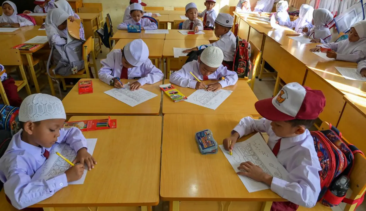 Dengan seragam lengkap, anak-anak sudah melakukan pembelajaran dengan menggunakan peralatan sekolah yang mereka bawa. (Chaideer MAHYUDDIN/AFP)