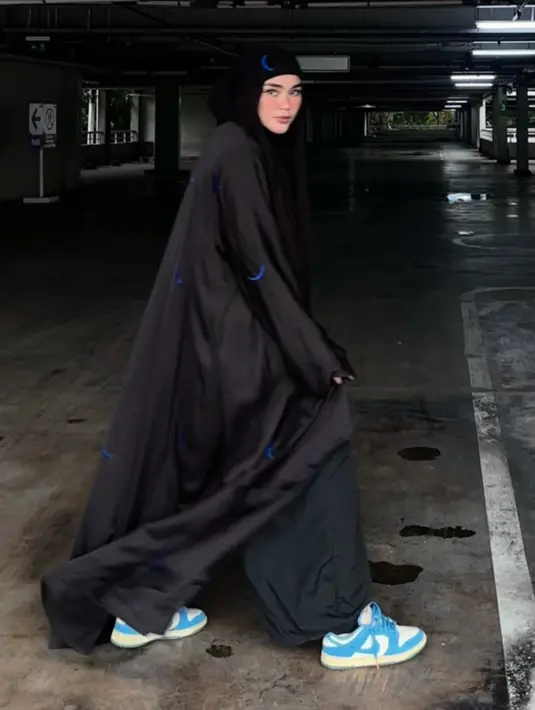 Sivia mengenakan kerudung hitam bergambar bulan sabit biru senada dengan abaya yang dijadikan outer, dipadukan celana hitam dan sneakers Nike biru.  [@siviazizah]
