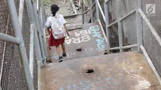 Seorang anak menuruni tangga di JPO di kawasan Tebet, Jakarta, Selasa (6/3). Kondisi JPO yang memprihatinkan menyebabkan sebagian warga lebih memilih untuk tidak menggunakannya karena membahayakan keselamatan. (Liputan6.com/Immanuel Antonius)