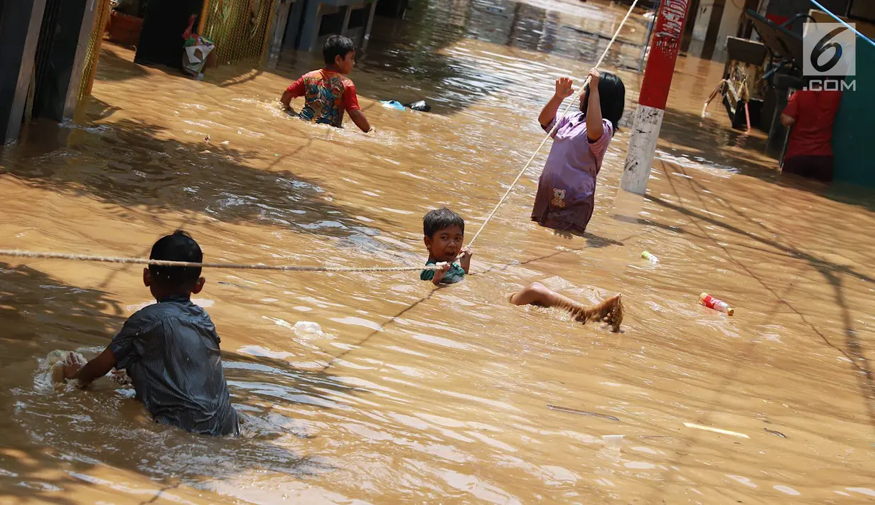 Anak-anak bermain saat banjir menggenangi kawasan Pejaten Timur, Jakarta, Jumat (26/4). Banjir yang berasal dari luapan Sungai Ciliwung tersebut merendam ratusan rumah warga hingga kedalaman lebih dari satu meter. (Liputan6.com/Immanuel Antonius)