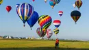 Sepasang kekasih berpelukan saat ratusan balon udara terbang di pangkalan udara Chambley-Bussieres, Hagéville, Prancis, Senin (29/7/2019). Acara ini disebut sebagai salah satu ajang pertemuan para pilot balon udara terbesar di dunia. (Jean-Christophe VERHAEGEN/AFP)