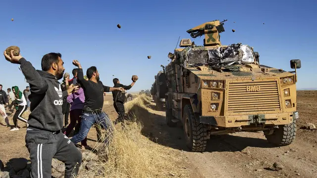 Sejumlah warga Kurdi melemparkan batu ke kendaraan militer Turki di dekat kota Al-Muabbadah, bagian timur laut Hassakah, Suriah (8/11/2019).