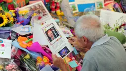Seorang warga membaca kartu ucapan duka atas meninggalnya mantan PM Singapura, Lee Kuan Yew di Singapore General Hospital, Senin (23/3/2015). Bapak bangsa Singapura ini meninggal dunia dalam usia 91 tahun karena mengidap pneumonia. (AFP PHOTO/Mohd Fyrol)