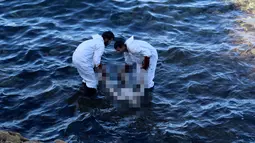 Petugas mengangkat mayat yang terapung di pantai di Kota Pesisir Tajoura, Libya, Minggu (4/12). Diduga orang yang tenggelam itu akan meninggalkan Libya karena berharap dapat menjadi imigran di negara lain. (REUTERS / Hani Amara)