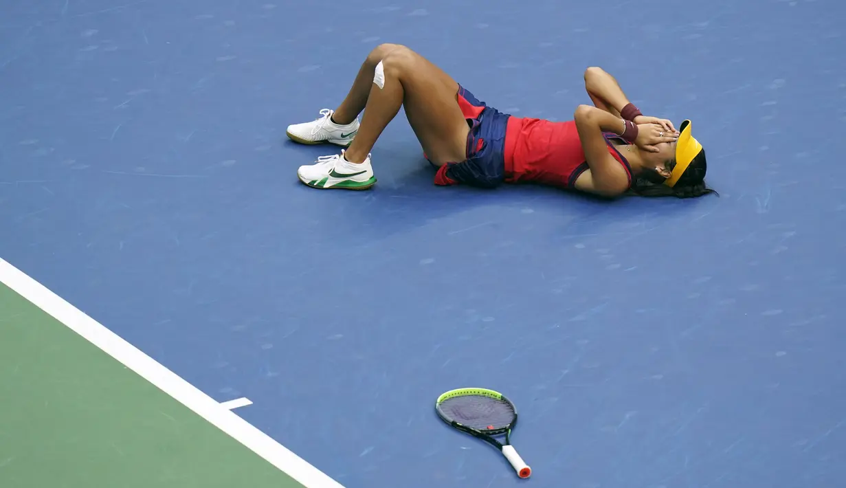 Petenis Inggris, Emma Raducanu berbaring di lapangan setelah mengalahkan Leylah Fernandez dari Kanada pada final tunggal putri US Open 2021 di Arthur Ashe Stadium, New York, Minggu (12/9/2021). Raducanu menang dua set langsung atas Leylah dengan 6-4 dan 6-3. (AP Photo/Frank Franklin II)