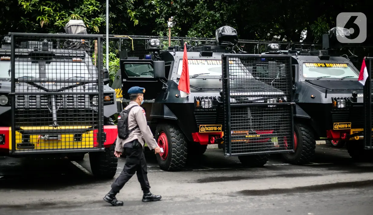 Petugas kepolisian melintas di depan mobil taktis yang disiapkan untuk pengamanan terkait pemeriksaan Rizieq Shihab di Polda Metro Jaya, Jakarta, Senin (7/12/2020). Polda Metro Jaya mengagendakan pemeriksaan terhadap Habib Rizieq Shihab (HRS) hari ini. (Liputan6.com/Faizal Fanani)