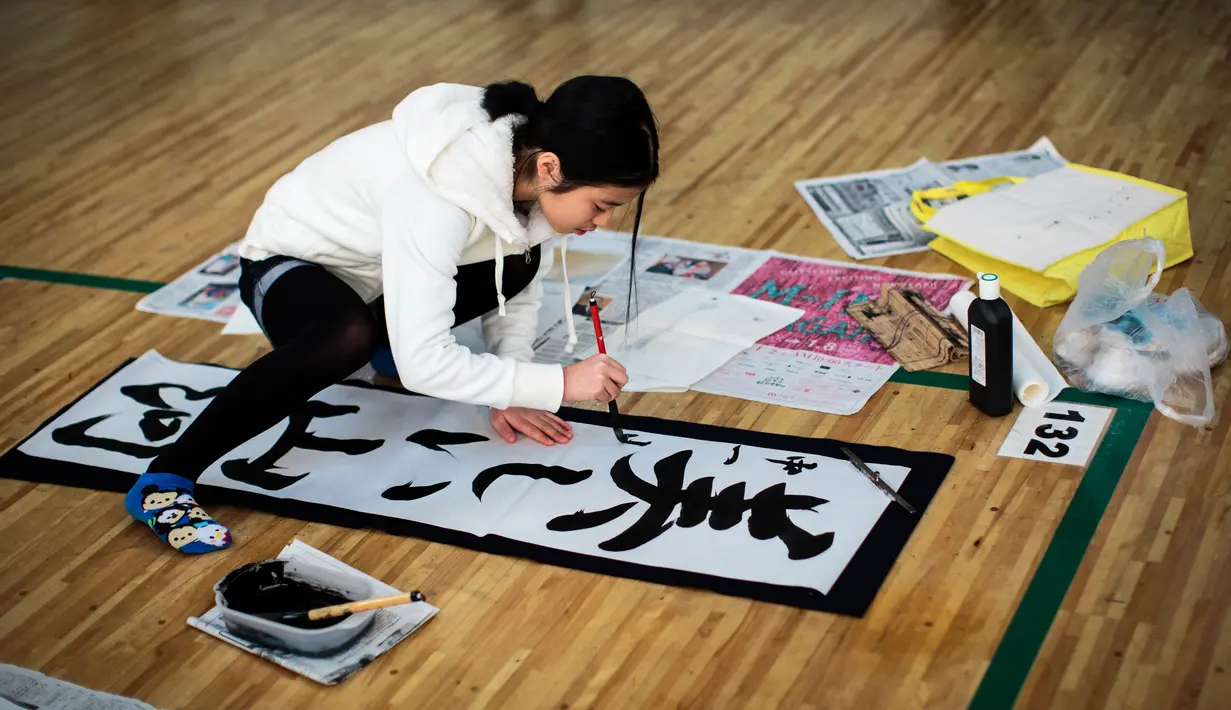 Seorang peserta menulis tulisan Jepang saat mengikuti lomba kaligrafi Tokyo, Jepang (5/1). Lomba yang digelar setiap tahun ini diikuti ribuan peserta. (AFP Photo/Behrouz Mehri)