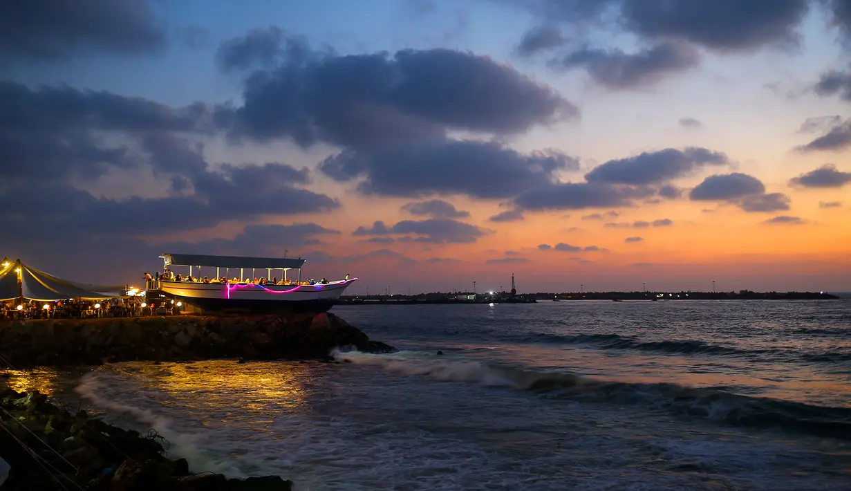 Pemandangan di sekitar restoran berbentuk perahu di tepi pantai Kota Gaza, Jalur Gaza, Palestina, Rabu (2/8). Restoran yang berada di atas batu karang tersebut menyuguhkan indahnya langit dengan gradasi warna biru dan oranye. (MOHAMMED ABED / AFP)