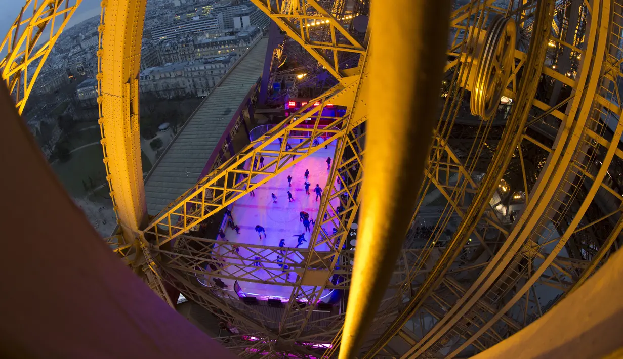 Pengunjung saat bermain ice skating di sebuah arena yang dibuka di lantai 1 Menara Eiffel, Paris, 19 Desember 2016. Tahun ini, arena ice skating tersebut buka sampai 19 Februari 2017 mendatang. (AFP PHOTO/JOEL SAGET)