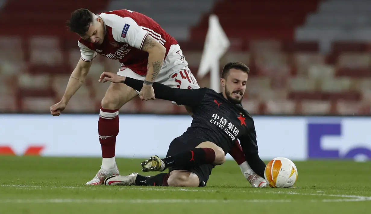 Gelandang Arsenal, Granit Xhaka berebut bola dengan gelandang Slavia Praha, Jakub Hromada pada pertandingan leg pertama perempat final Liga Europa di Stadion Emirates di London, Jumat (9/4/2021). Arsenal bermain imbang atas Slavia Praha 1-1.  (AP Photo/Alastair Grant)