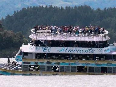 Penumpang terlihat berada di atas kapal wisata Almirante sesaat sebelum tenggelam di sebuah waduk di Kolombia barat daya, Minggu (25/6). Sedikitnya sembilan orang meninggal dunia dan 28 lainnya hilang dalam peristiwa itu. (Juan QUIROZ/AFPP)