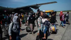Seorang wanita membawa anaknya ketika mereka tiba di Surabaya, Kamis (4/10). Banyak anak-anak yang terpisah dari keluarganya setelah bencana gempa-tsunami melanda Palu dan Donggala pada 28 September. (AFP Photo/Juni Kriswanto)