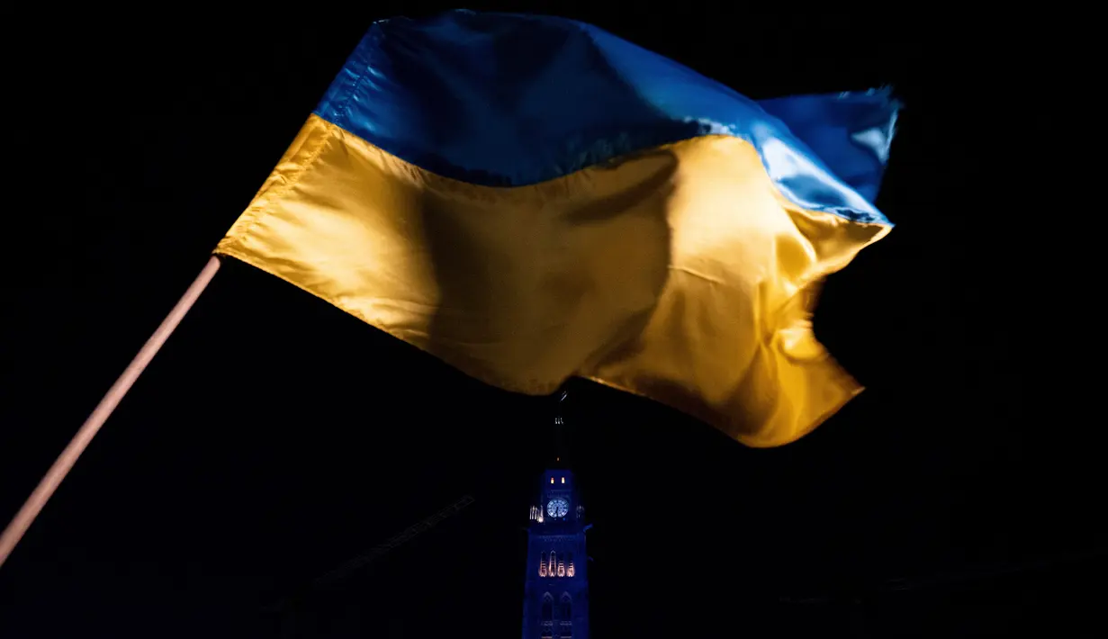 Bendera Ukraina terlihat saat Centre Block of Parliament Hill diterangi dengan warna biru dan kuning Ukraina saat peringatan satu tahun sejak invasi Rusia ke Ukraina di Parliament Hill, Ottawa, Ontario, Kanada, 24 Februari 2023. (Spencer Colby/The Canadian Press via AP)