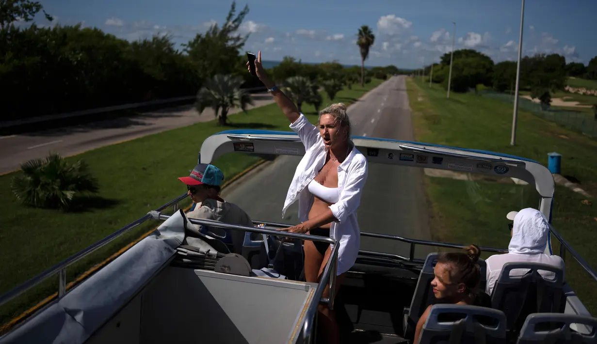 Turis Rusia melambai dari bus wisata saat melakukan tur kota Varadero di Kuba, Rabu (29/9/2021). Pihak berwenang di Kuba mulai melonggarkan pembatasan COVID-19 di beberapa kota seperti Havana dan Varadero. (AP Photo/Ramon Espinosa)