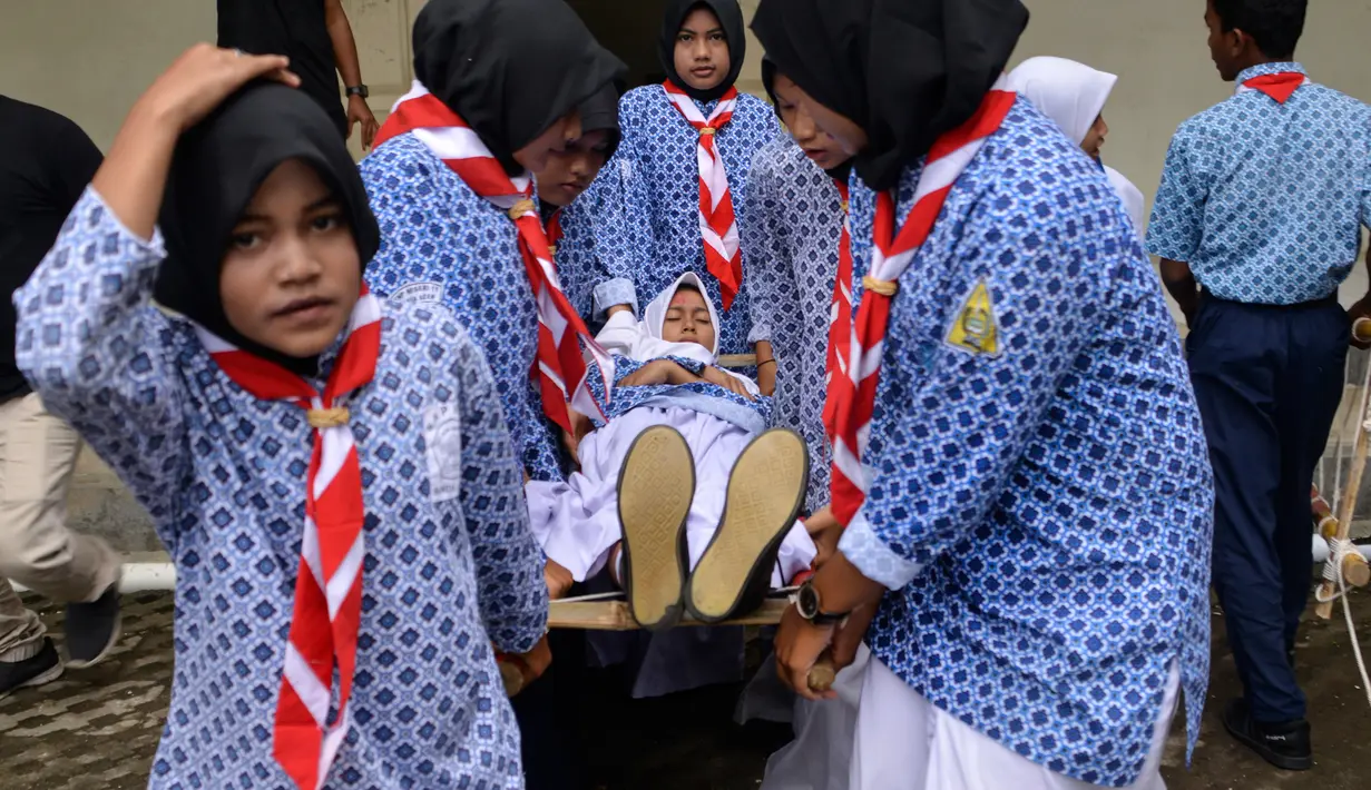 Sejumlah siswa memberikan pertolongan pertama saat simulasi bencana gempa dan tsunami di sebuah sekolah di Banda Aceh, Aceh, Rabu (9/10/2019). Para siswa dibekali wawasan tanggap darurat bencana dan pemberian pertolongan pertama pada korban gempa. (Photo by CHAIDEER MAHYUDDIN / AFP)