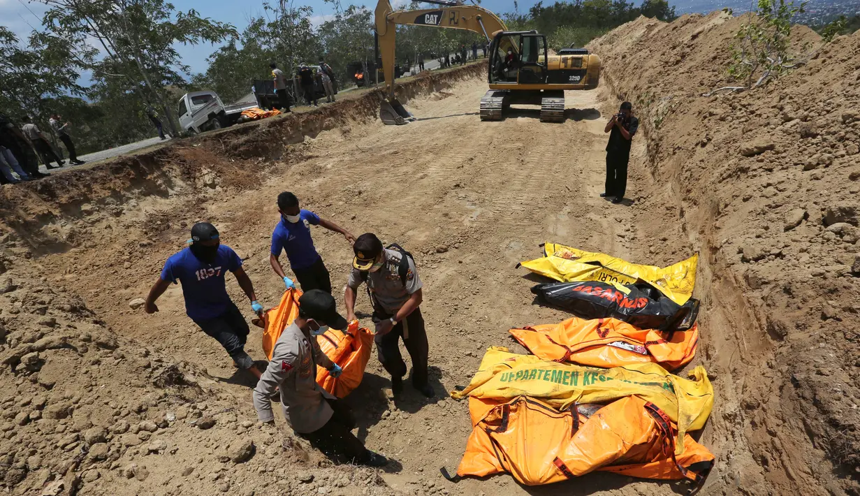 Petugas membawa jenazah korban gempa dan tsunami untuk dimakamkan massal di Palu, Sulawesi Tengah, Senin (1/10). (AP Photo/Tatan Syuflana)