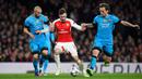 Aaron Ramsey berusaha melewati dua gelandang tangguh Barcelona, Javier Mascherano dan ivan rakitic pada leg pertama 16 besar Liga Champions di Stadion Emirates, Inggris (24/2). Barcelona menang atas Arsenal dengan skor 2-0. (Reuters/Dylan Martinez)