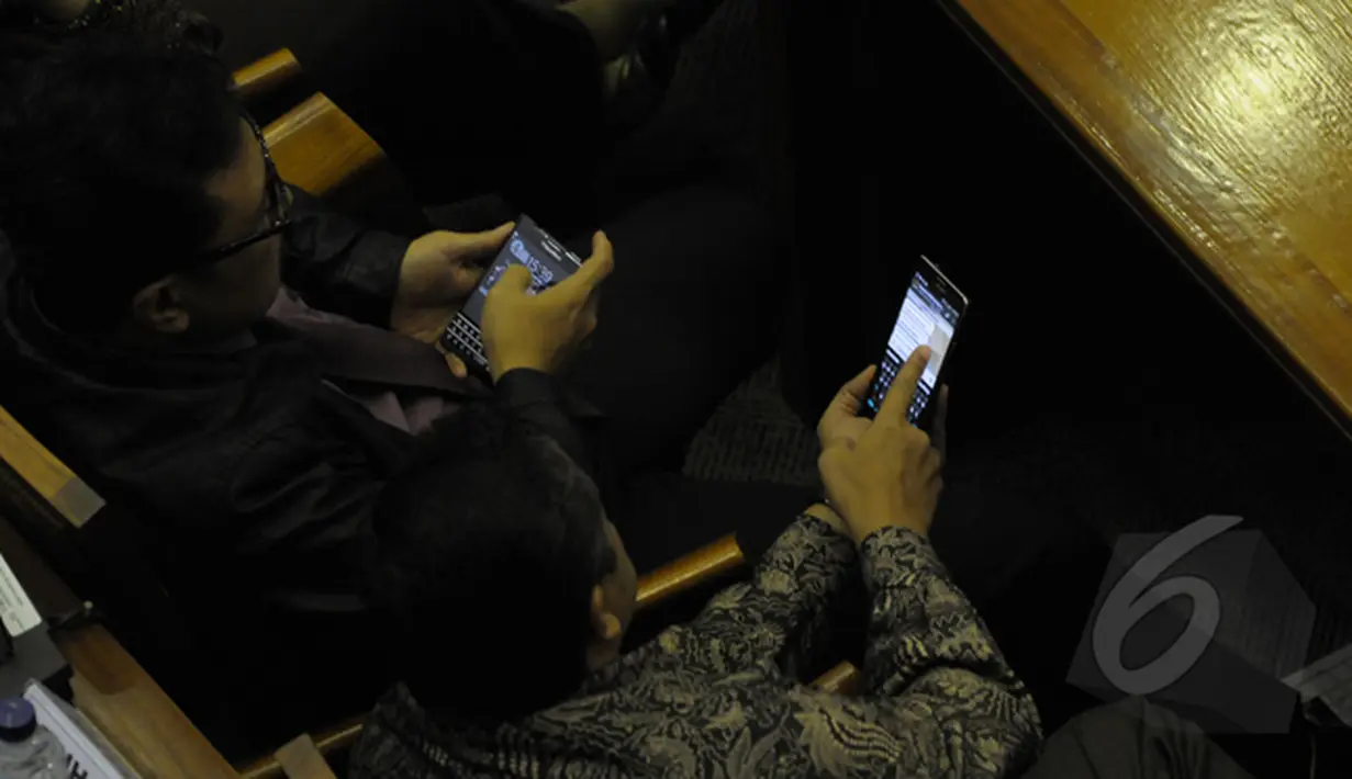 Saat rapat Paripurna sejumlah anggota dewan sibuk dengan ponselnya. Seorang anggota dewan memperlihatkan sesuatu di ponsel kepada rekannya, Jakarta (09/02/2015). (Liputan6.com/Andrian M Tunay)