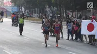 Pelari maraton Jepang, Hiroto Inoue bersaing dengan Elhassan Elabbassi dari Bahrain saat memasuki garis finis lomba Asian Games 2018 di jalan Sudirman, Jakarta, Sabtu (25/8). Hiroto menjadi pemenang lari maraton 42 kilometer. (Merdeka.com/Imam Buhori)