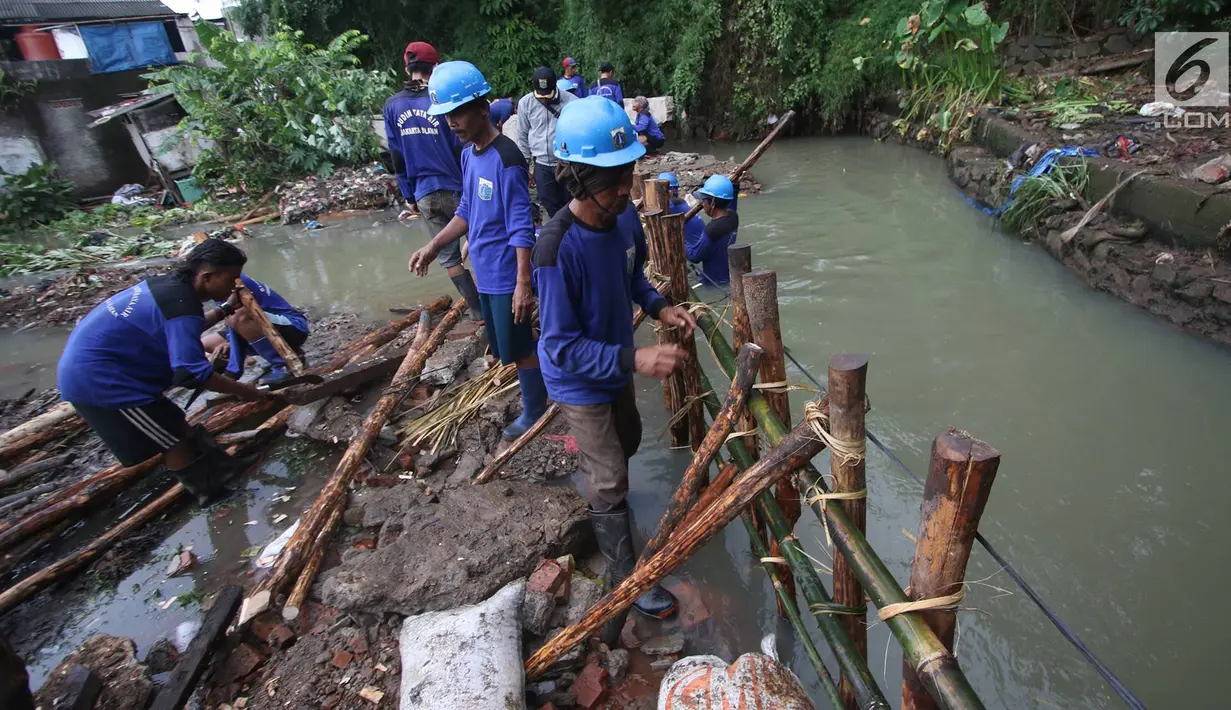 Pekerja menyelesaikan pembuatan tanggul darurat di kawasan Jatipadang, Jakarta, Rabu (22/11). Jebolnya tanggul Kali Pulo di kawasan tersebut menyebabkan puluhan rumah terendam banjir. (Liputan6.com/Immanuel Antonius)