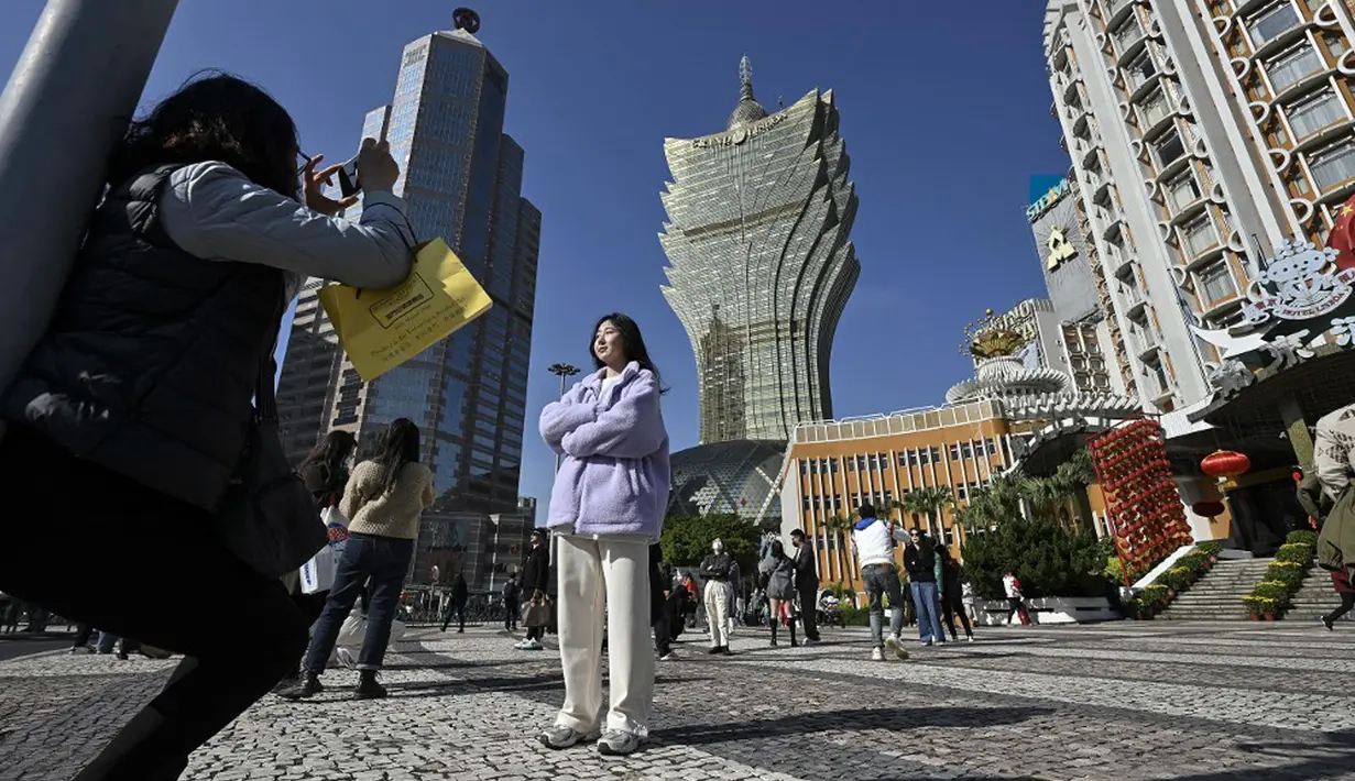 Pelancong asal China mengambil foto di luar kompleks Kasino Grand Lisboa di daerah kantong China, Makau, 17 Januari 2023. Ledakan pariwisata China yang diharapkan selama liburan Tahun Baru Imlek minggu depan tampaknya akan lebih cepat terjadi. (Peter PARKS/AFP)