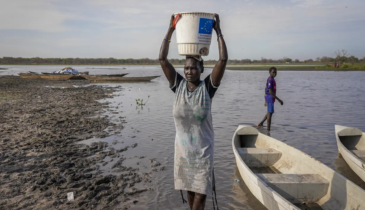 Seorang perempuan membawa air di kepalanya dari rawa, dengan sebagian besar daerah tidak memiliki akses ke air minum bersih karena banjir bertahun-tahun yang belum pernah terjadi sebelumnya, di Canal-Pigi County, Sudan Selatan pada 4 Mei 2023. (AP Photo/Sam Mednick)